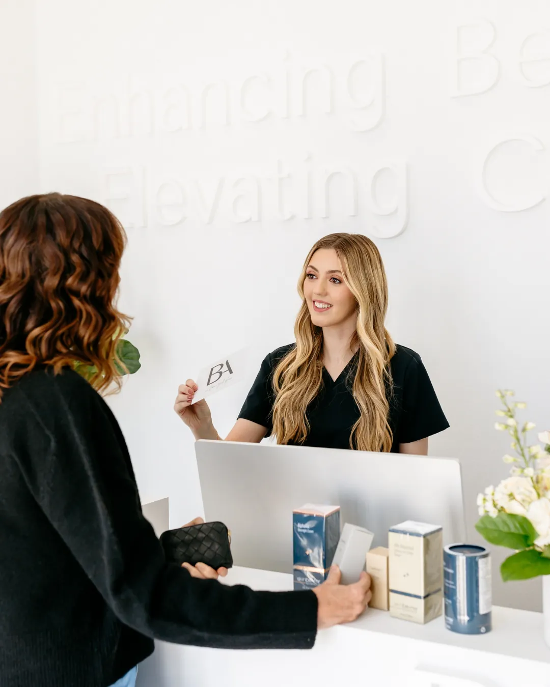 A med-spa receptionist welcoming a client at the front desk